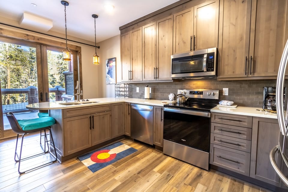 Your fully-equipped kitchen features warm wood cabinets, stainless steel appliances, and a cozy breakfast bar perfect for morning coffee.