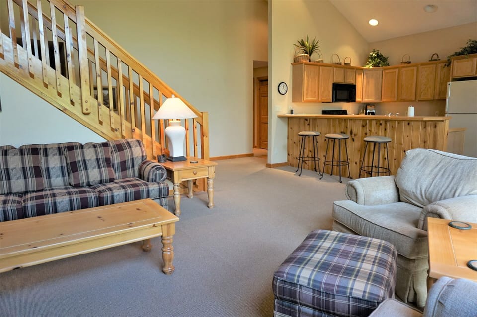 Living Room features cathedral ceiling, 2 story windows, sofa bed, knotty pine.