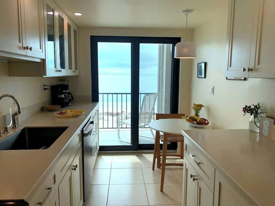 Full kitchen with dishware, cookware, glassware, coffee maker, blender, kitchen aid mixer, and toaster.   The sliding glass door leads to private patio #1.