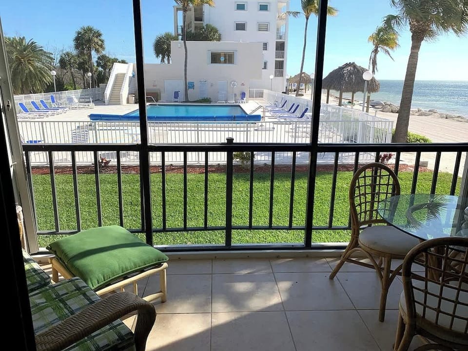 Screened-in patio overlooking large heated pool and beach.