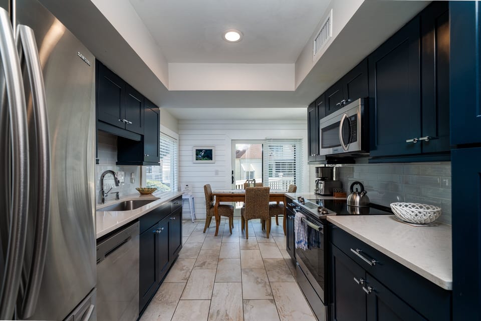Kitchen has stainless steel appliances and painted cabinets.