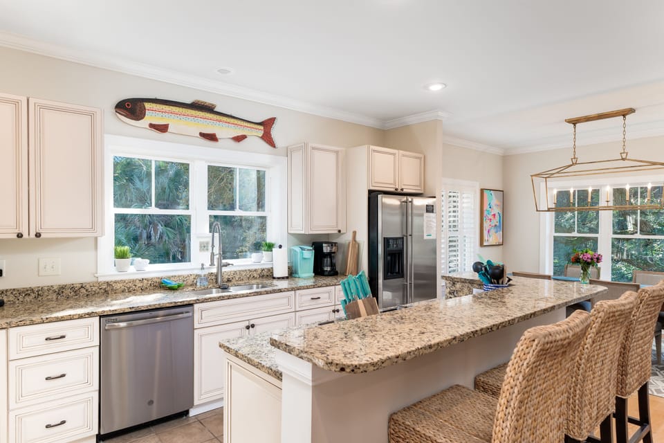 Fully equipped kitchen with bar and three counter stools.