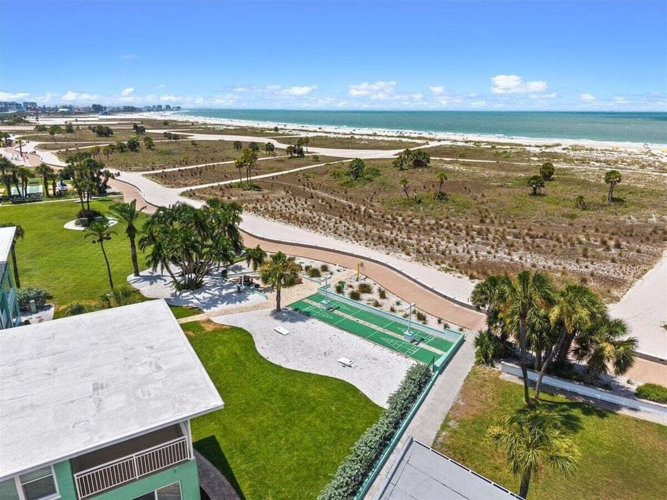 Aerial view of our resort grounds, featuring shuffleboard courts, a picnic area with grills and a fire pit, and direct access to the Treasure Island Boardwalk and beach.