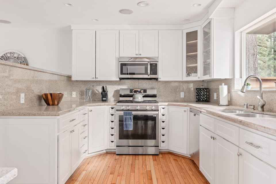 - Bright modern kitchen with stainless steel stove  
- White cabinetry and granite counters throughout  
- Fully stocked for cooking family cabin meals