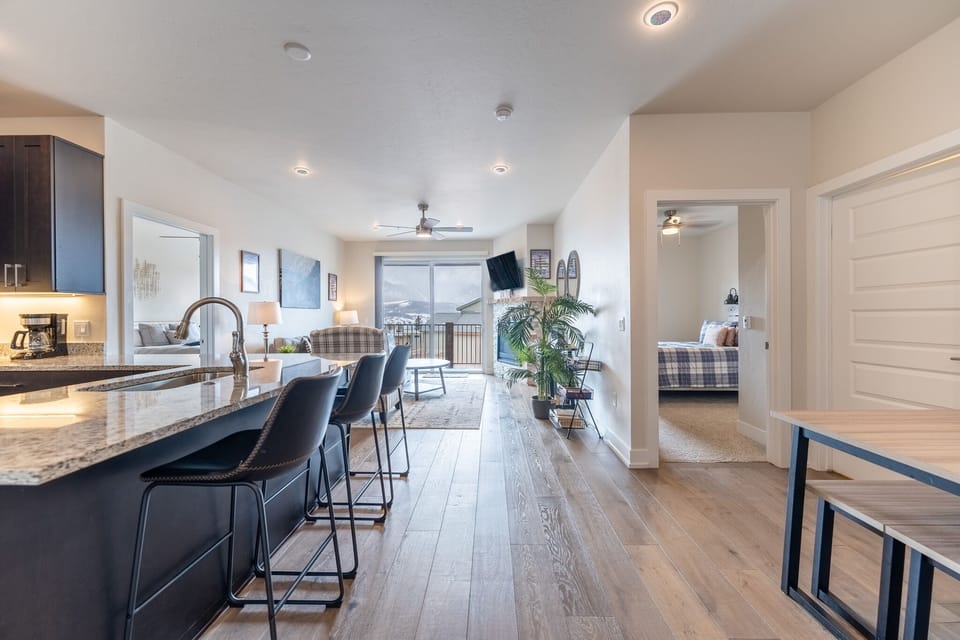 Step into your modern retreat where sleek kitchen meets cozy living space, with mountain views through floor-to-ceiling windows.