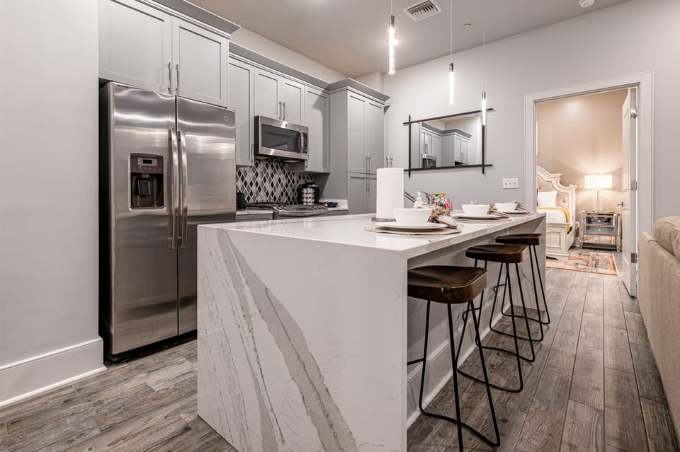 Cook and dine with ease in the fully stocked kitchen, featuring stainless steel appliances, a gas range, and basic cookware. Entertain at the large island with seating for 3 or enjoy meals at the dining table with 4 seats.