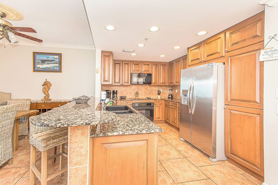 Your fully equipped kitchen features granite counters, stainless appliances, and an island perfect for preparing fresh meals during your beach getaway.