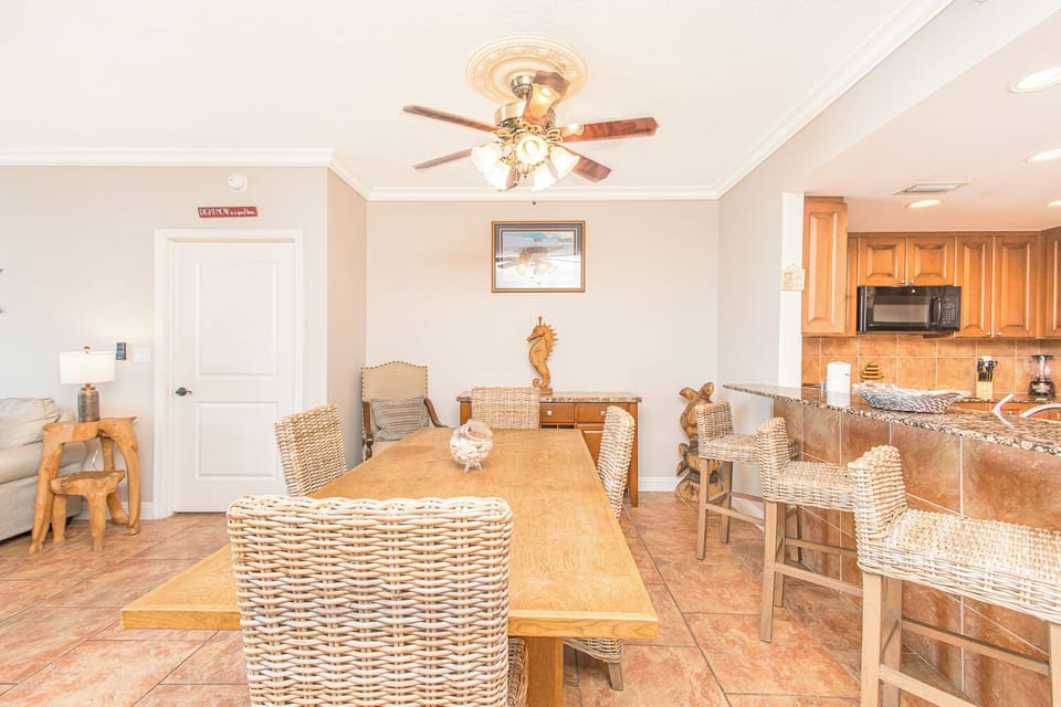 Step into your bright dining area with coastal charm—wicker seating, nautical accents, and a ceiling fan overhead. The open layout flows seamlessly into your fully equipped kitchen.