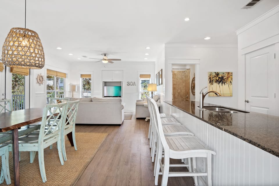 Open-concept living and dining area with coastal flair, bar seating, and abundant natural light—ideal for gathering and relaxing on your 30A escape.