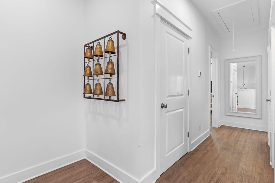Coastal hallway with unique bell wall décor and warm wood floors, adding charm and character to this inviting 30A getaway.