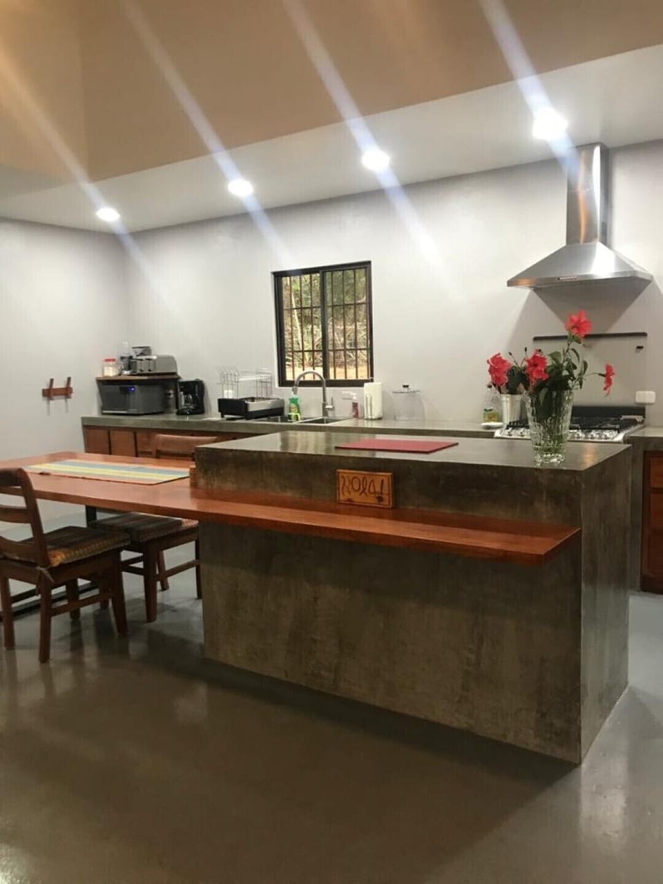Kitchen and solid wood table extending from concrete island: room hub.