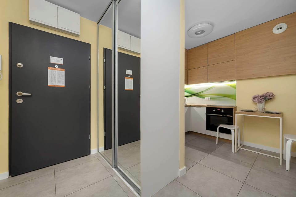 The entryway features a large mirrored wardrobe that reflects the kitchen and enhances the sense of space.