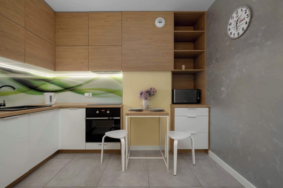 Detailed view of the kitchen reveals upper wooden cabinets and a practical dining spot with white stools.