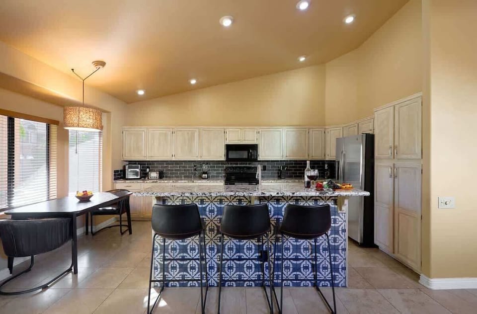 Fully equipped kitchen featuring stainless-steel appliances, kitchen island with bar seating for 3 guests, and an informal dining table with seating for 2 guests.