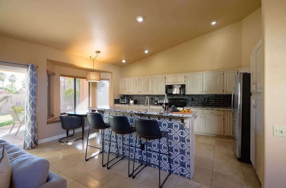 Fully equipped kitchen featuring stainless-steel appliances, kitchen island with bar seating for 3 guests, and an informal dining table with seating for 2 guests.