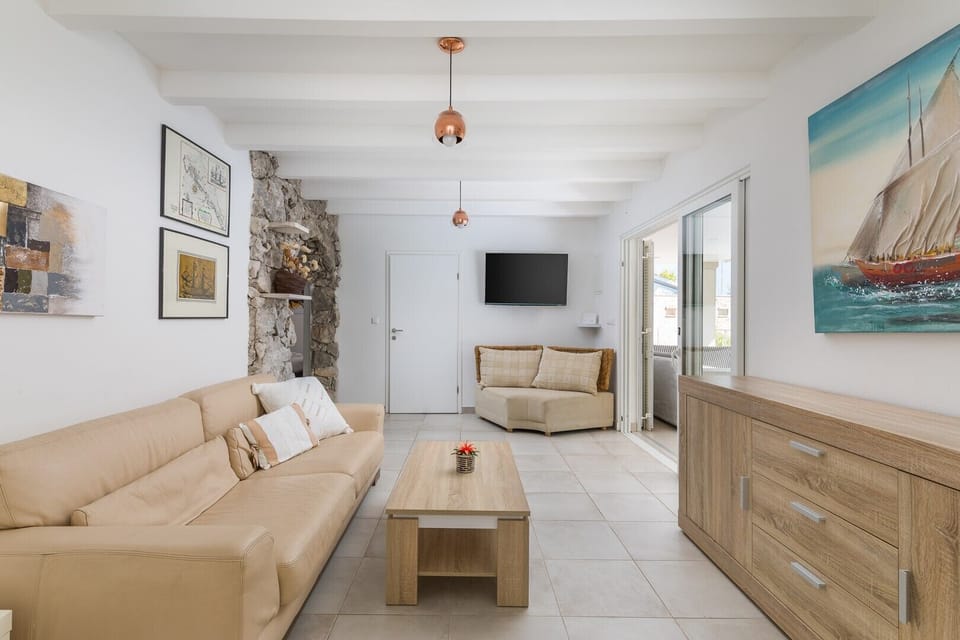 The interior of Croatia luxury villa for rent Anemos on the island of Hvar with comfortable leather furniture, a wooden table, an LCD TV and a wooden chest of drawers