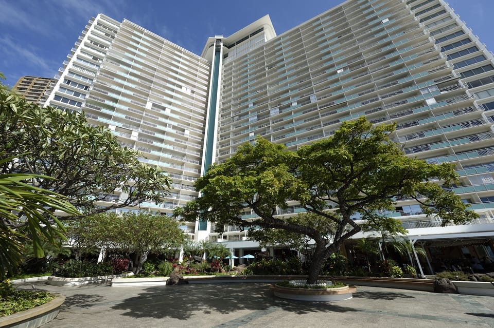 Modern high-rise vacation rental towers surround a landscaped courtyard entrance, offering a blend of urban convenience and tropical charm in a prime location.