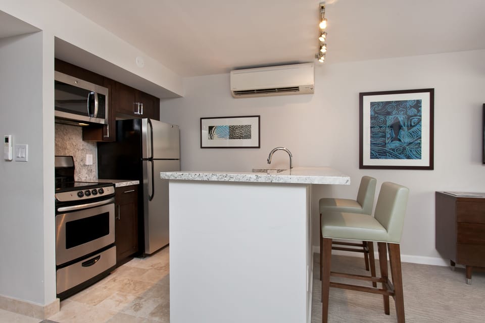 Your modern kitchen features stainless steel appliances, granite countertops, and a breakfast bar with stylish seating—perfect for morning coffee or casual meals at home.