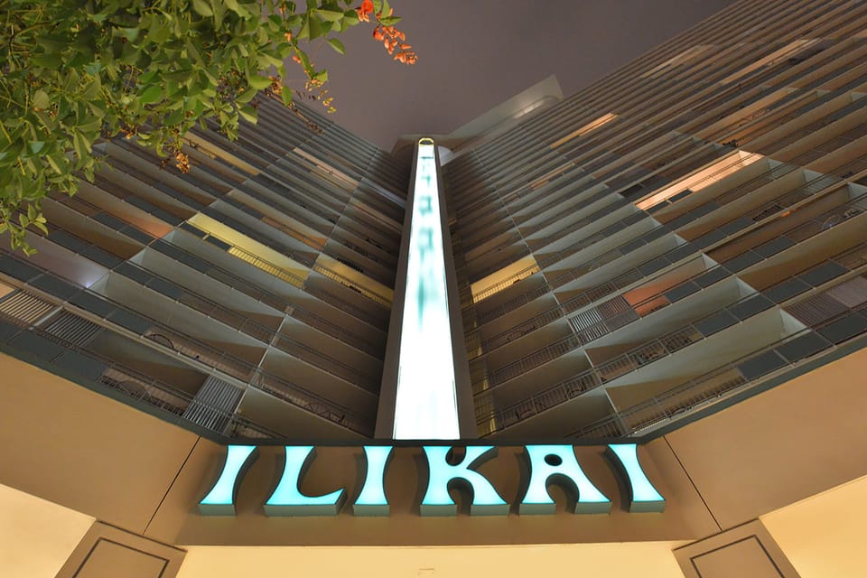 Modern multi-story property with distinctive illuminated signage and contemporary architectural design featuring extensive balconies and glass elements.