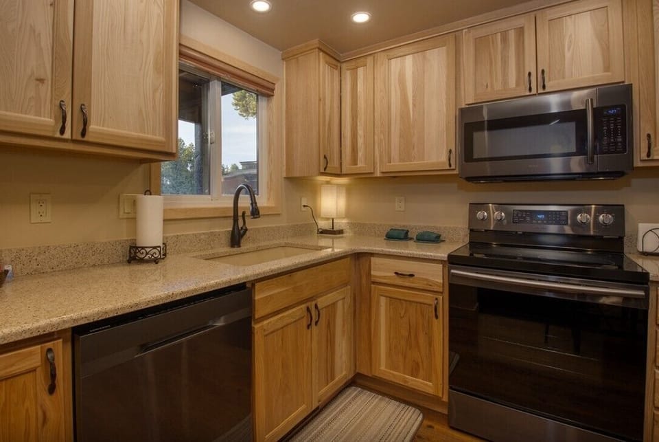 Your fully equipped kitchen features warm wood cabinetry, granite countertops, and modern stainless steel appliances, perfect for preparing home-cooked meals during your stay.