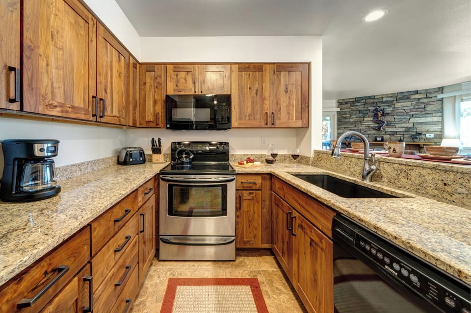 Kitchen includes granite countertops, wood cabinets, stainless steel oven and black appliances.