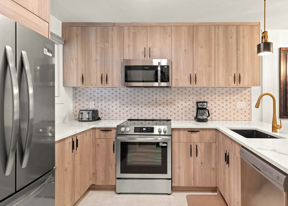 The beautiful kitchen has stainless steel appliances, warm wood cabinets, and white accents.