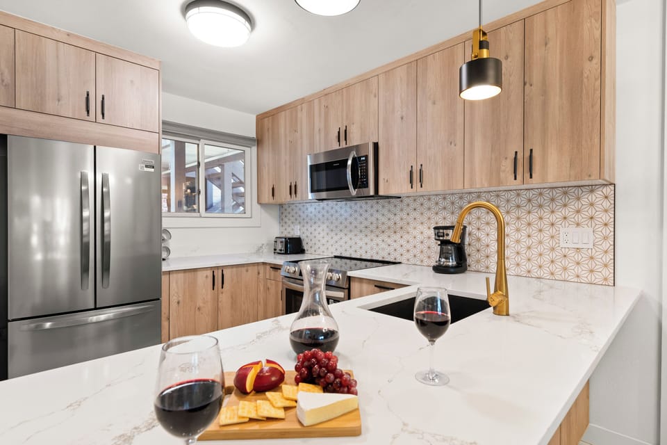 The remodeled kitchen has white oak cabinets, white counter and white and gold backsplash.