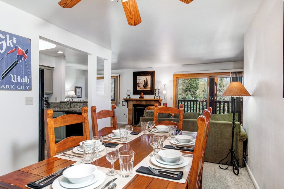 The dining area has a wood table, seating and place settings for 6, and is situated next to the open floorplan living room.