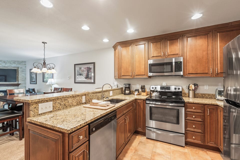 Snow Flower 135's kitchen with medium colored wood cabinets, granite counters, and stainless steel appliances.