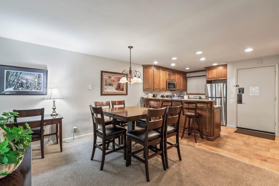 Snow Flower 135's dining area with a wood table, 6 dining chairs, and chandelier and open concept kitchen.