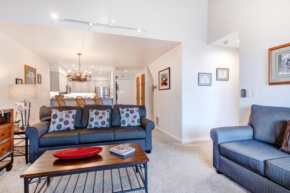 The living room offers new grey upholstered couches and wood furniture.