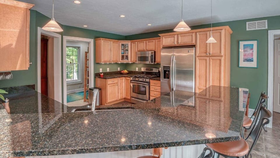 Kitchen with fridge with an ice dispenser and freezer. Gas stove