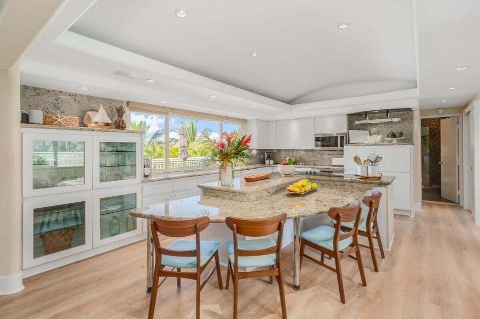 A spacious kitchen featuring a large island with seating, granite countertops, and plenty of natural light