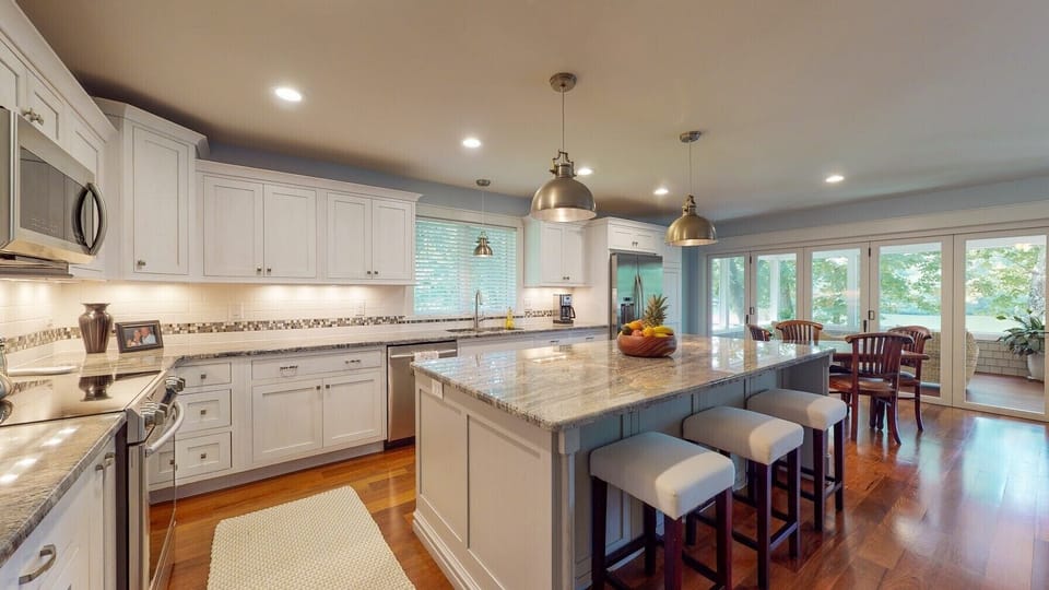 Open concept kitchen with white washed oak cabinets and hard wood floors