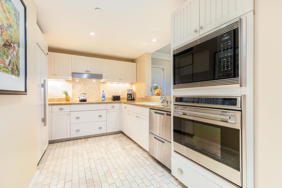Modern kitchen with stainless appliances and sleek tile flooring.