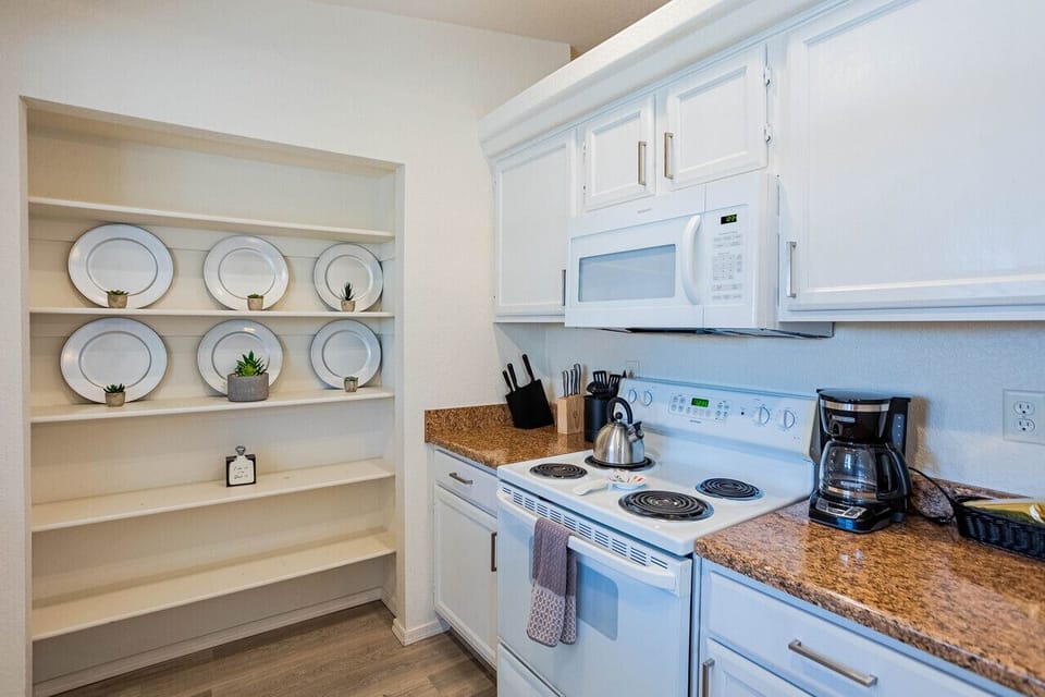 Fully equipped, open shelf pantry, stocked with coffee, condiments, toaster, blender, rice maker, and other cooking, baking, and dining essentials.