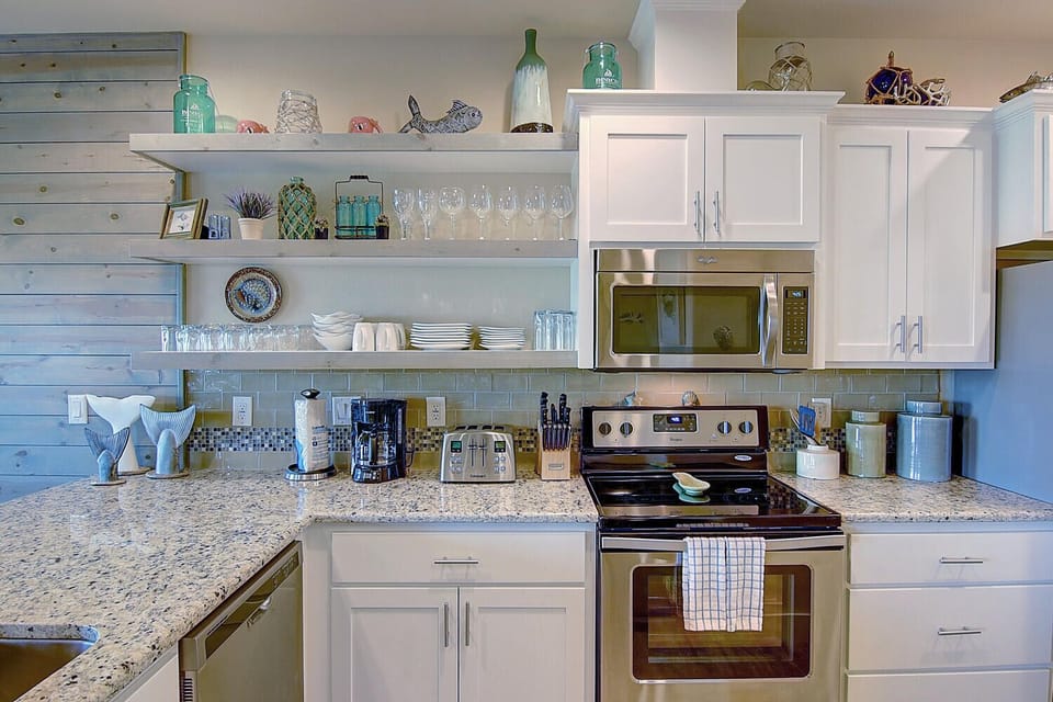 Your fully equipped kitchen awaits with granite countertops, stainless steel appliances, and coastal-inspired touches for memorable meal preparation.
