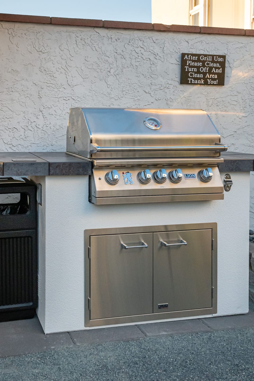 Sparkling clean, brand new large Wolf barbecue grill w/ utencils near fire pit. 
