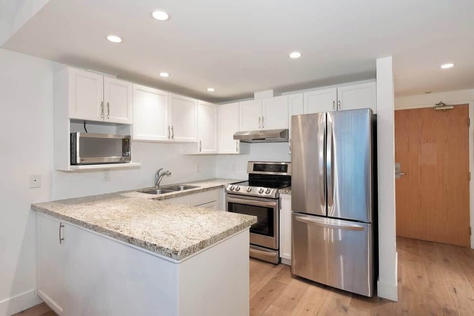 - Modern kitchen with stainless steel appliances and granite countertops  
- Bright open space with white cabinets and warm wooden floors  
- Perfect setup for cooking and entertaining during your Whistler stay  