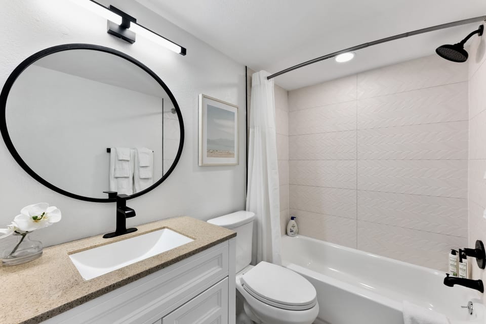 Upgraded bathroom with a sleek faucet round mirror and bright airy design