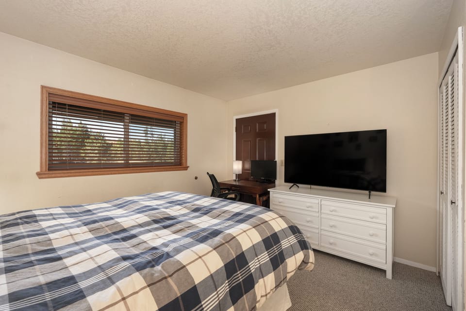 Relax in your cozy bedroom with plaid bedding, work desk, and large TV for evening entertainment.
