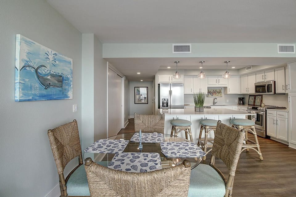 Your open-concept dining and kitchen space features coastal charm with wicker chairs, pendant lighting, and modern appliances for memorable meals together.