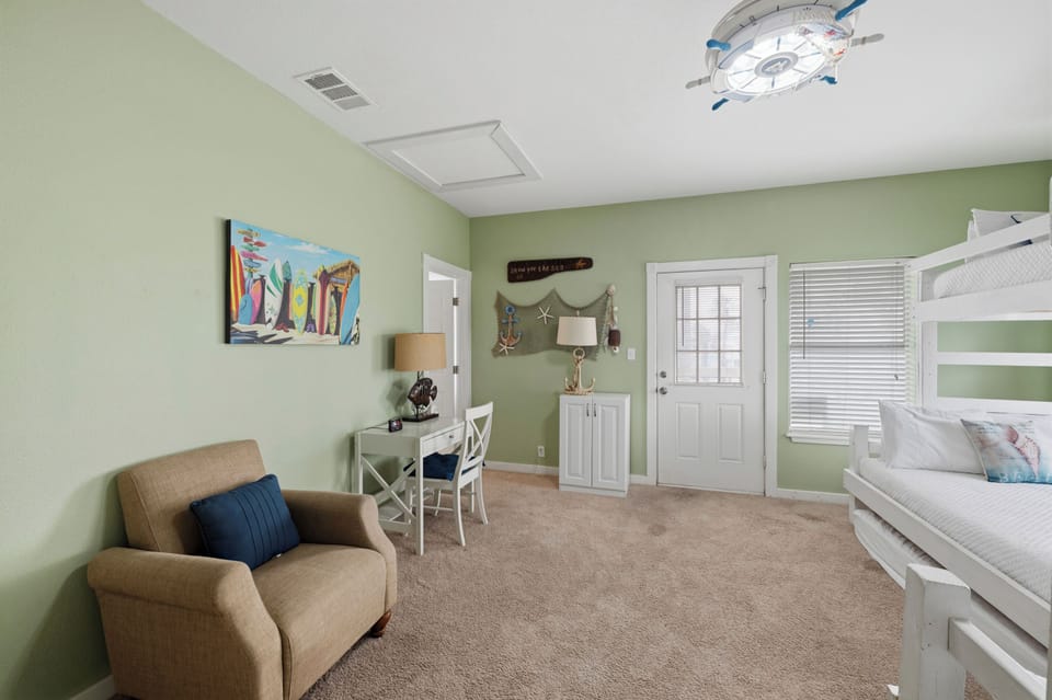 Step into your breezy coastal retreat, where nautical touches and soft green walls create a peaceful escape. Relax in the armchair, enjoy beachside art, and unwind in your serene sanctuary.
