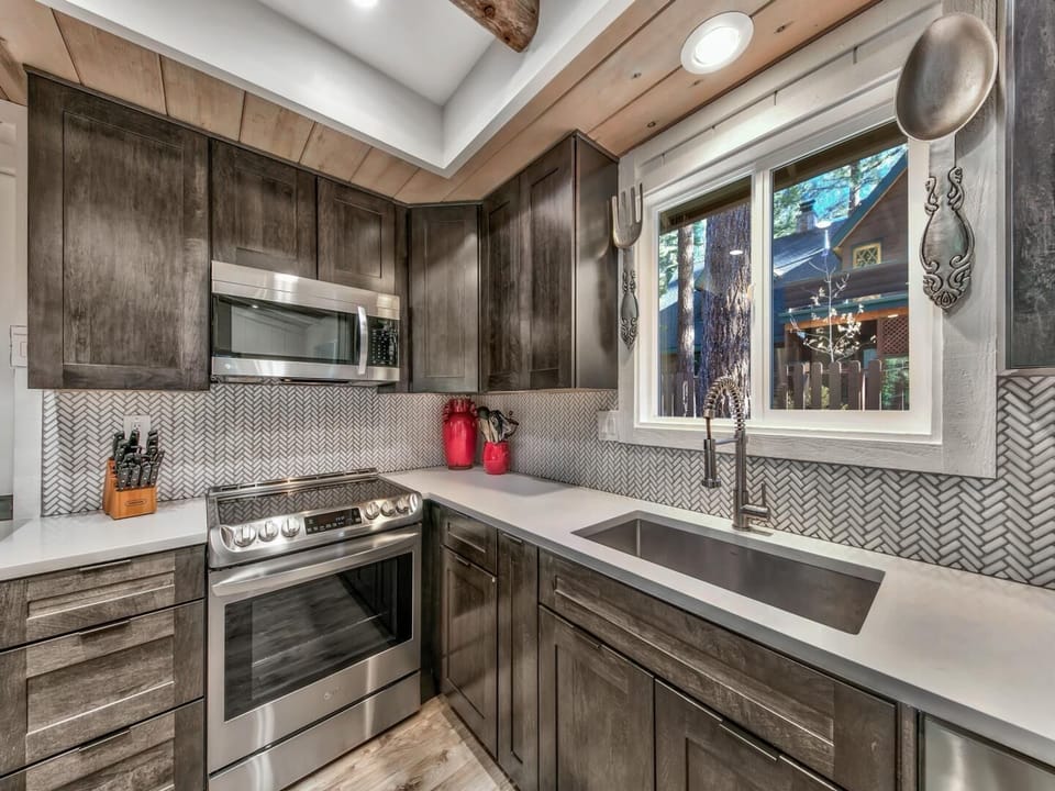 Your fully equipped kitchen features rich wood cabinets, modern appliances, and stylish herringbone backsplash for effortless meal preparation.