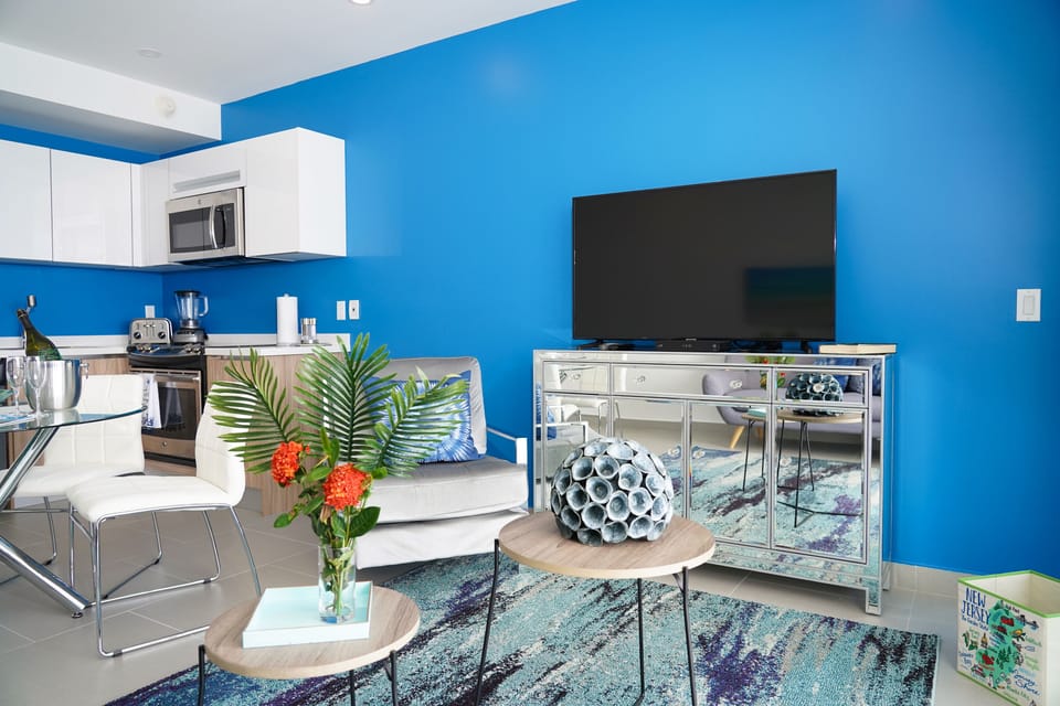 Settle into your vibrant, open-plan space where bold blue walls energize the room. Enjoy cooking in the sleek kitchen, relaxing on the sofa, and unwinding with entertainment at your fingertips.