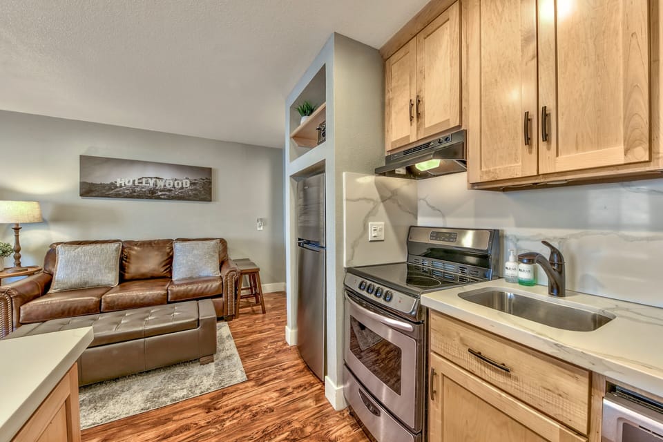 Your open-concept suite blends modern kitchen convenience with cozy living comfort, featuring warm wood cabinetry and leather seating for relaxing evenings.