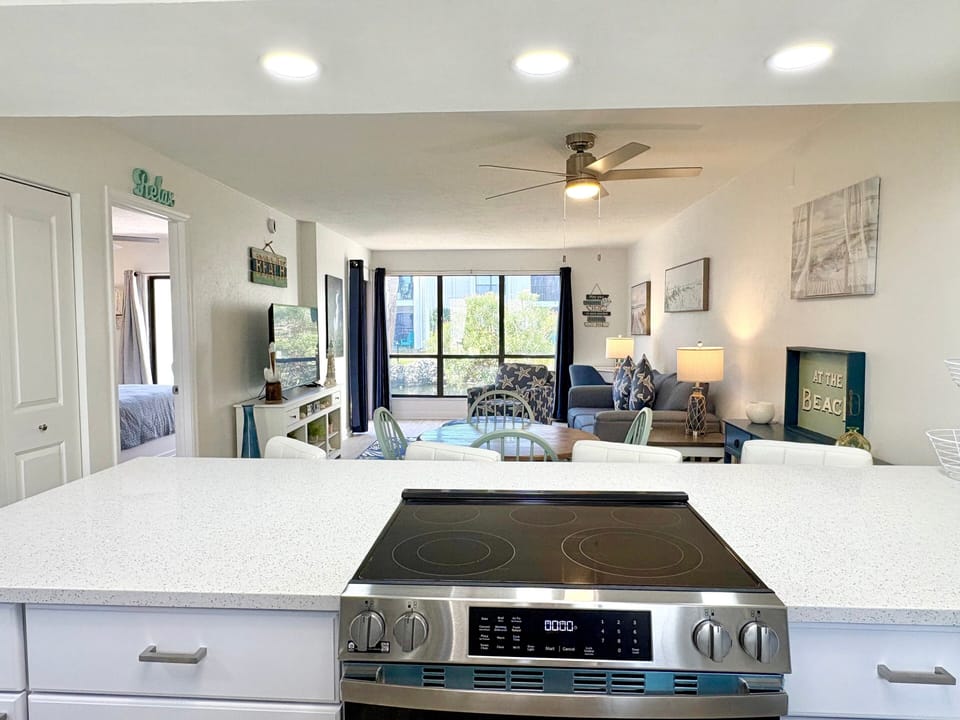 Open living room with ceiling fan and large windows with natural light