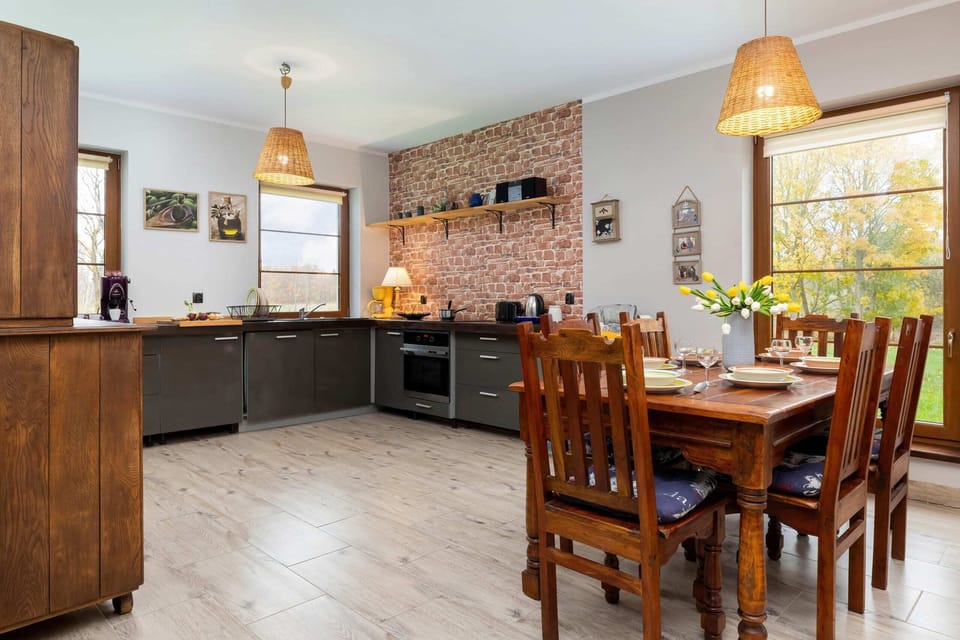 A dining space with a wooden table, six chairs, and a chandelier, located near a large window with outdoor views.