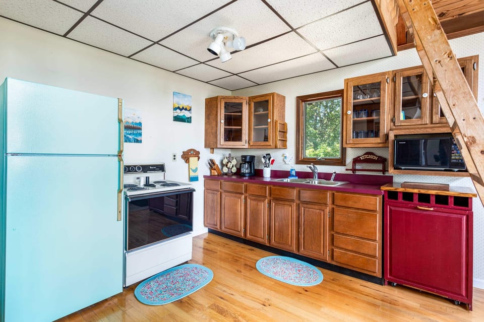 Cozy kitchen with wooden cabinets and a window overlooking greenery.