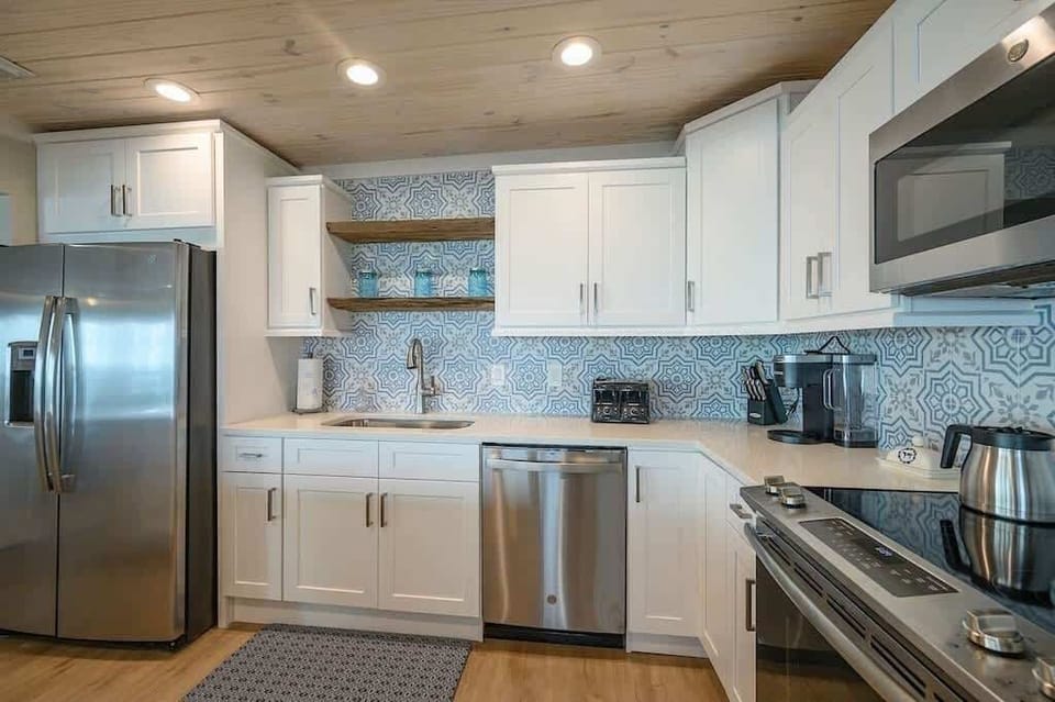 - Clean layout with white cabinets and open shelving makes the kitchen feel easy to use - Stainless steel appliances and patterned tile add a fun and fresh coastal style - Everything you need is right here for coffee, snacks, or full meals at home